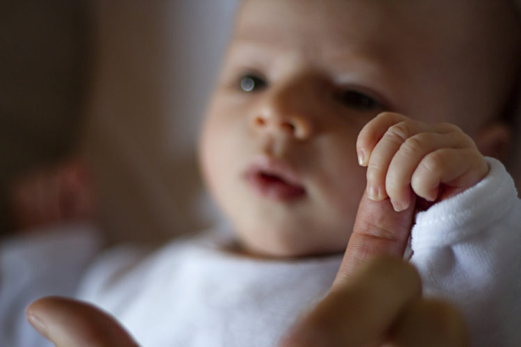Bébé de 01 mois qui tient le doigt de son papa